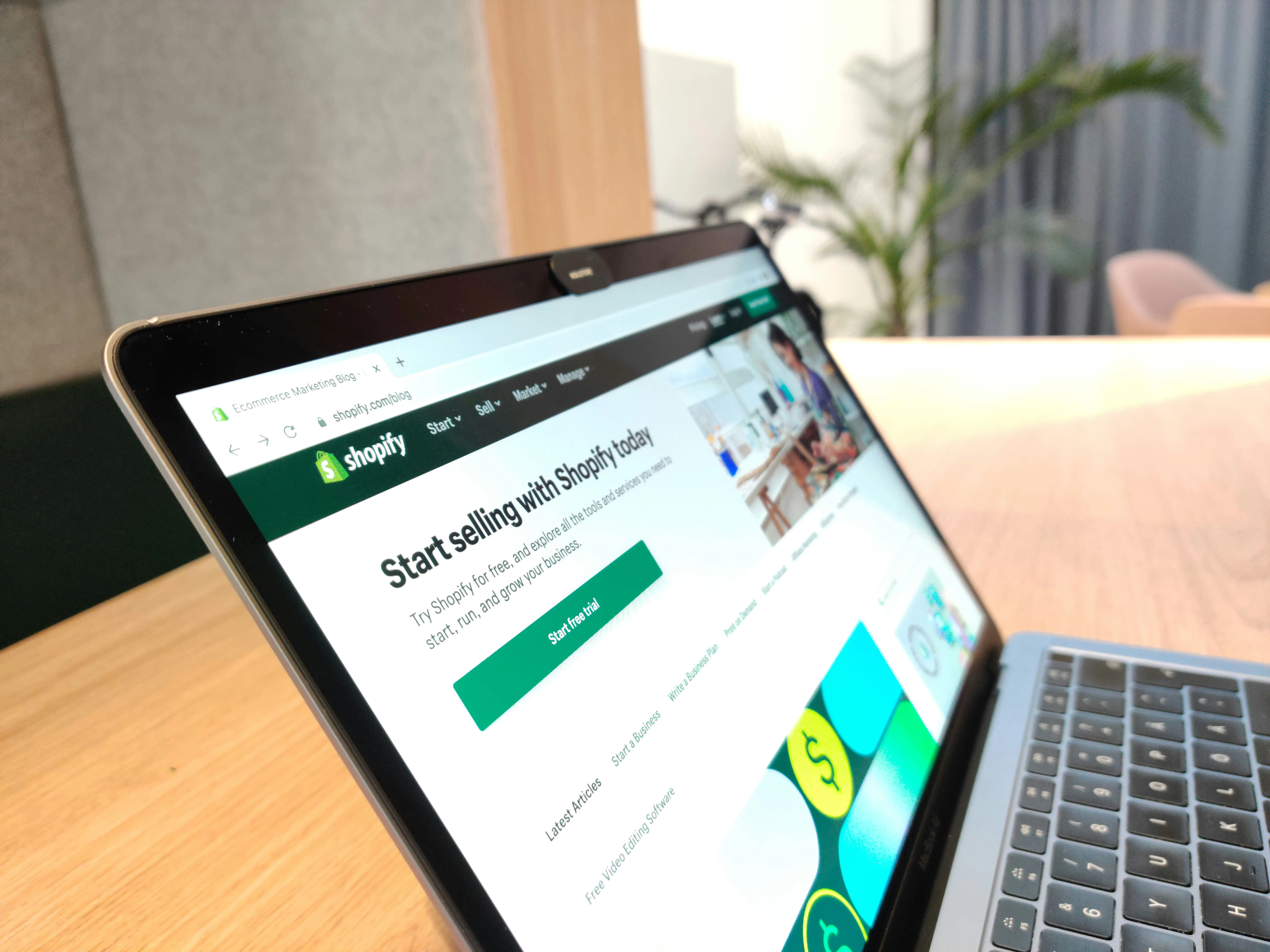 Un ecran de laptop afișând un magazin online cu diverse produse, înconjurat de elemente grafice care sugerează optimizare SEO și trafic, cu logo-ul Google subtil în fundal.