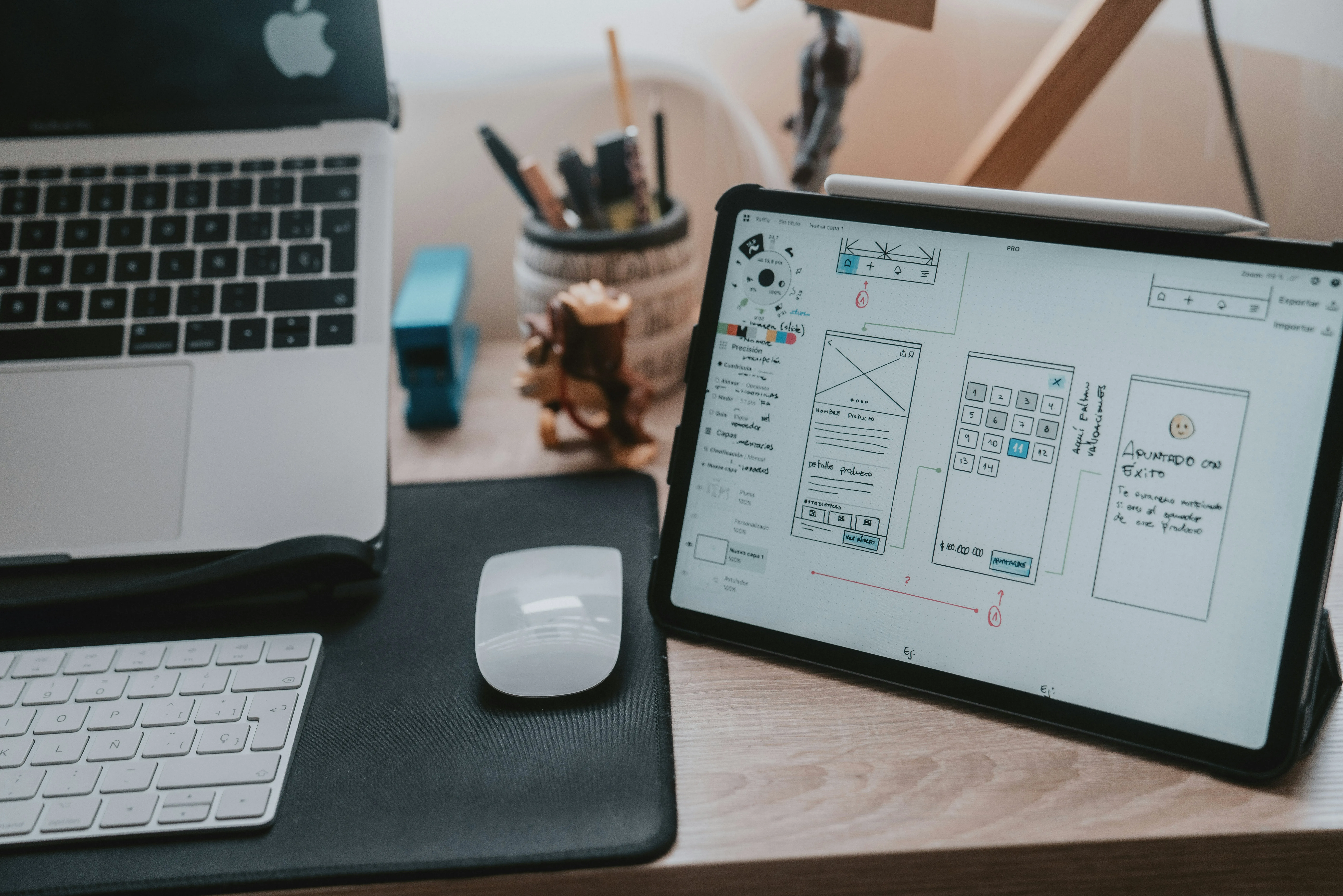 Un laptop MacBook deschis și o tabletă afișând un wireframe de design UI/UX, simbolizând procesul de web design și dezvoltare.