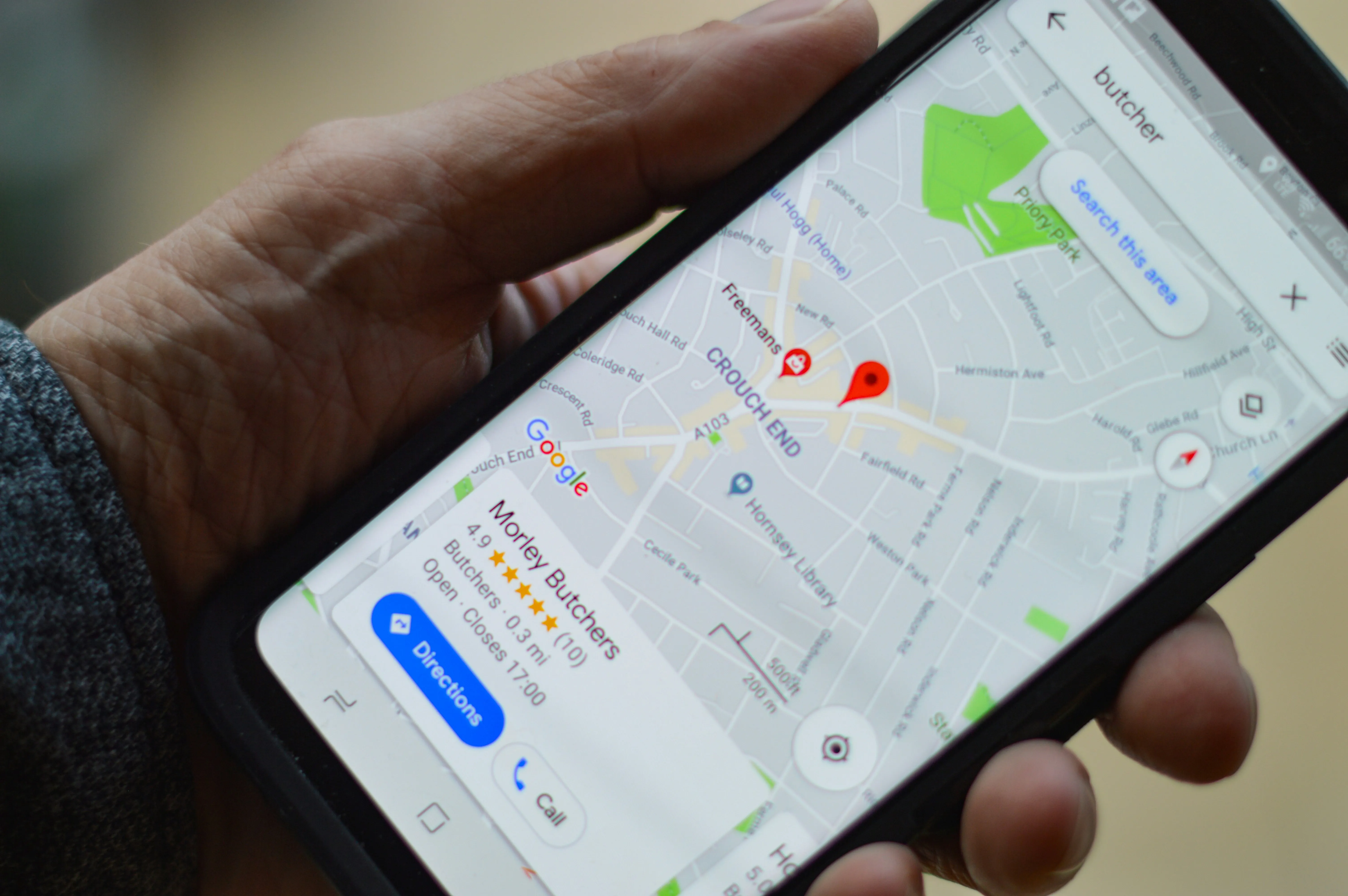 O hartă digitală pe un ecran de smartphone cu locații evidențiate și simboluri de SEO, reprezentând vizibilitatea crescută în căutările locale Google.